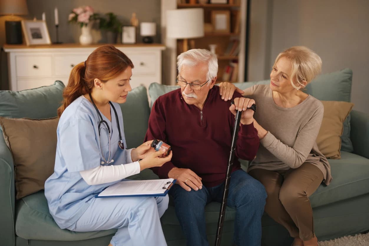 A nurse discussing medication with a man and woman in their home